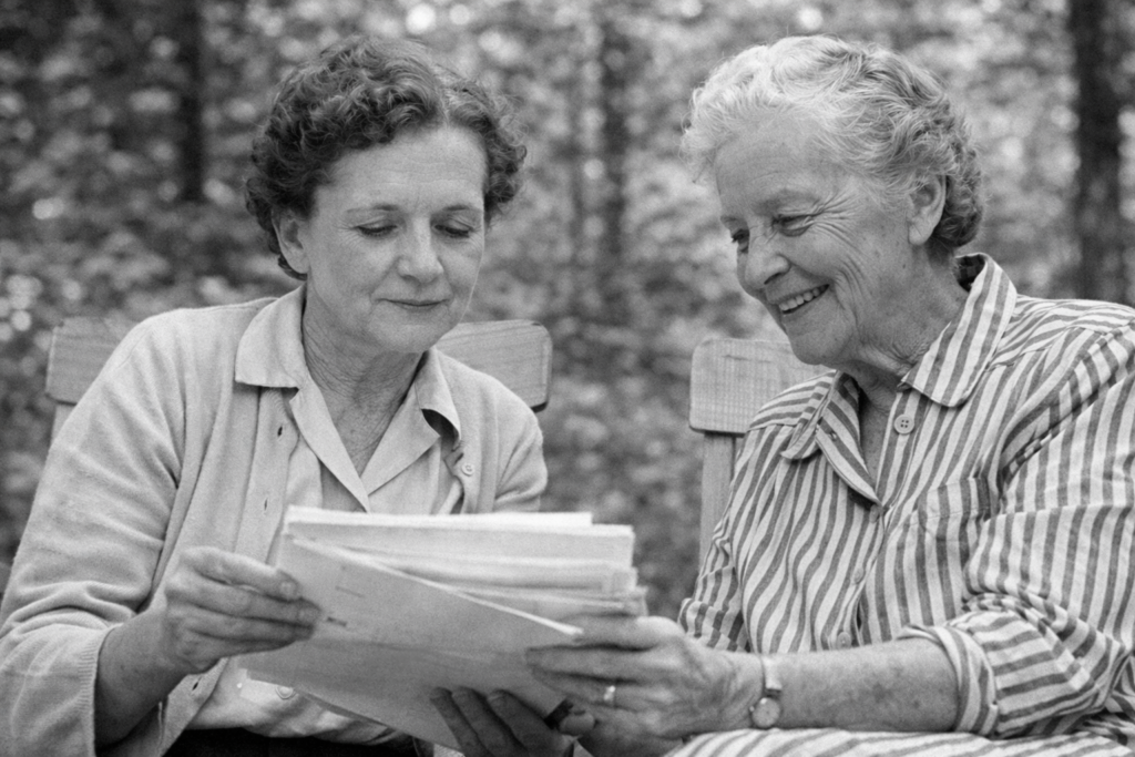 Rachel Carson and Dorothy Freeman reviewing papers together outdoors