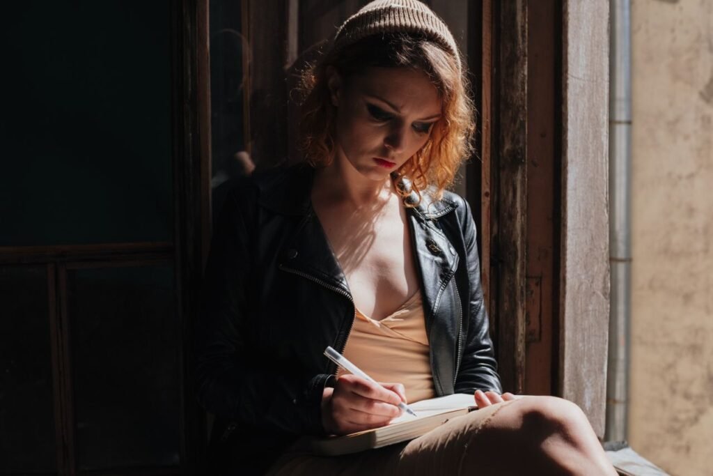 Woman writing in a journal while reflecting on blood dreams, emotions, past actions, and waking life experiences.
